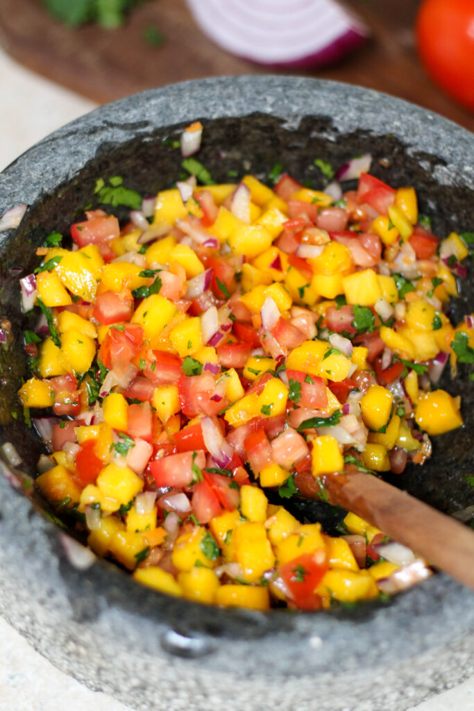 Mango habanero salsa in a bowl with wooden spoon