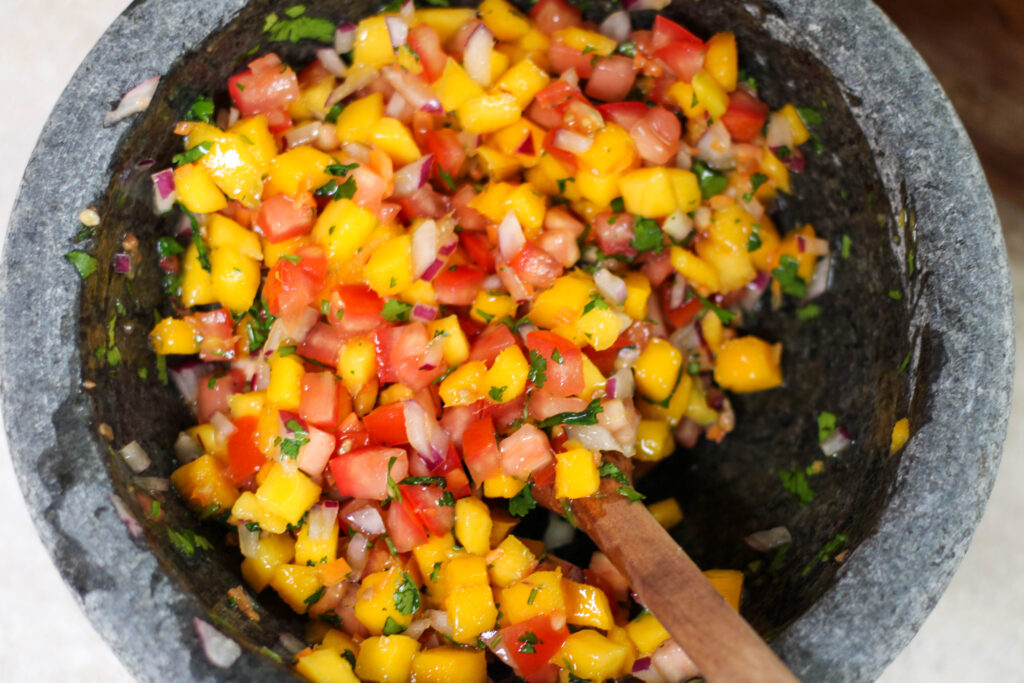 Mango habanero salsa in a bowl with wooden spoon