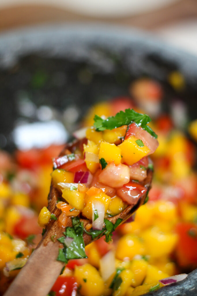 Mango habanero salsa in a bowl with wooden spoon