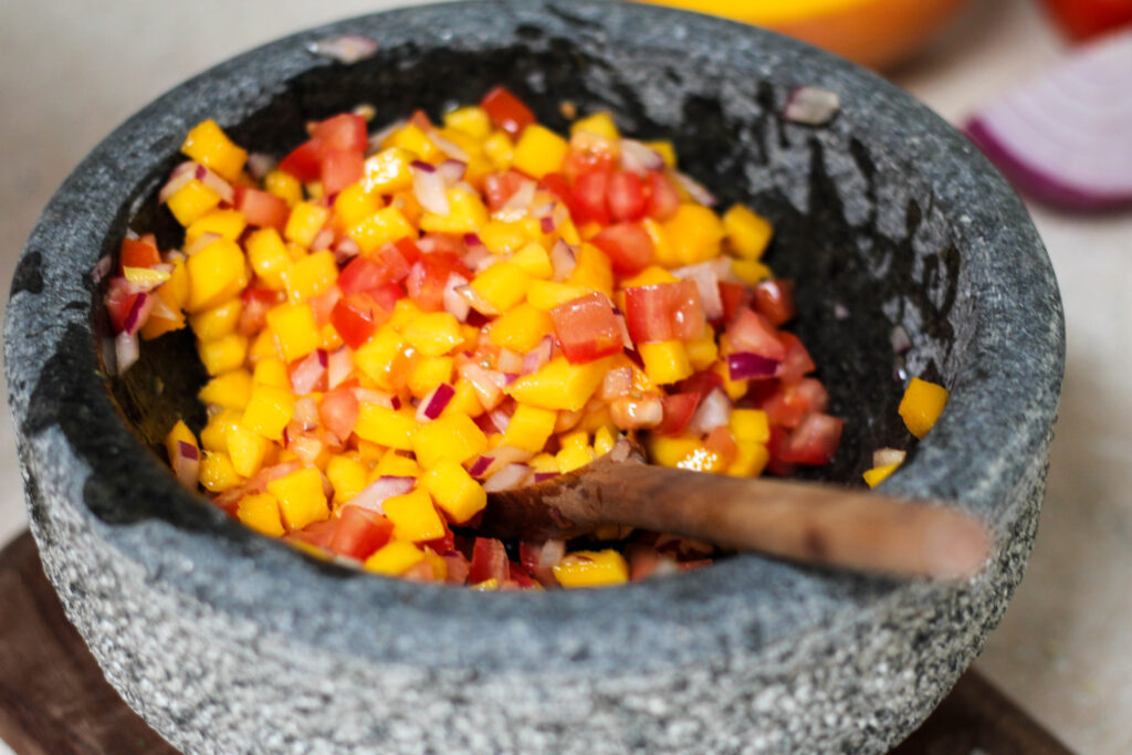 Diced tomato, mango and red onion in a mortar and pestle or molcajete